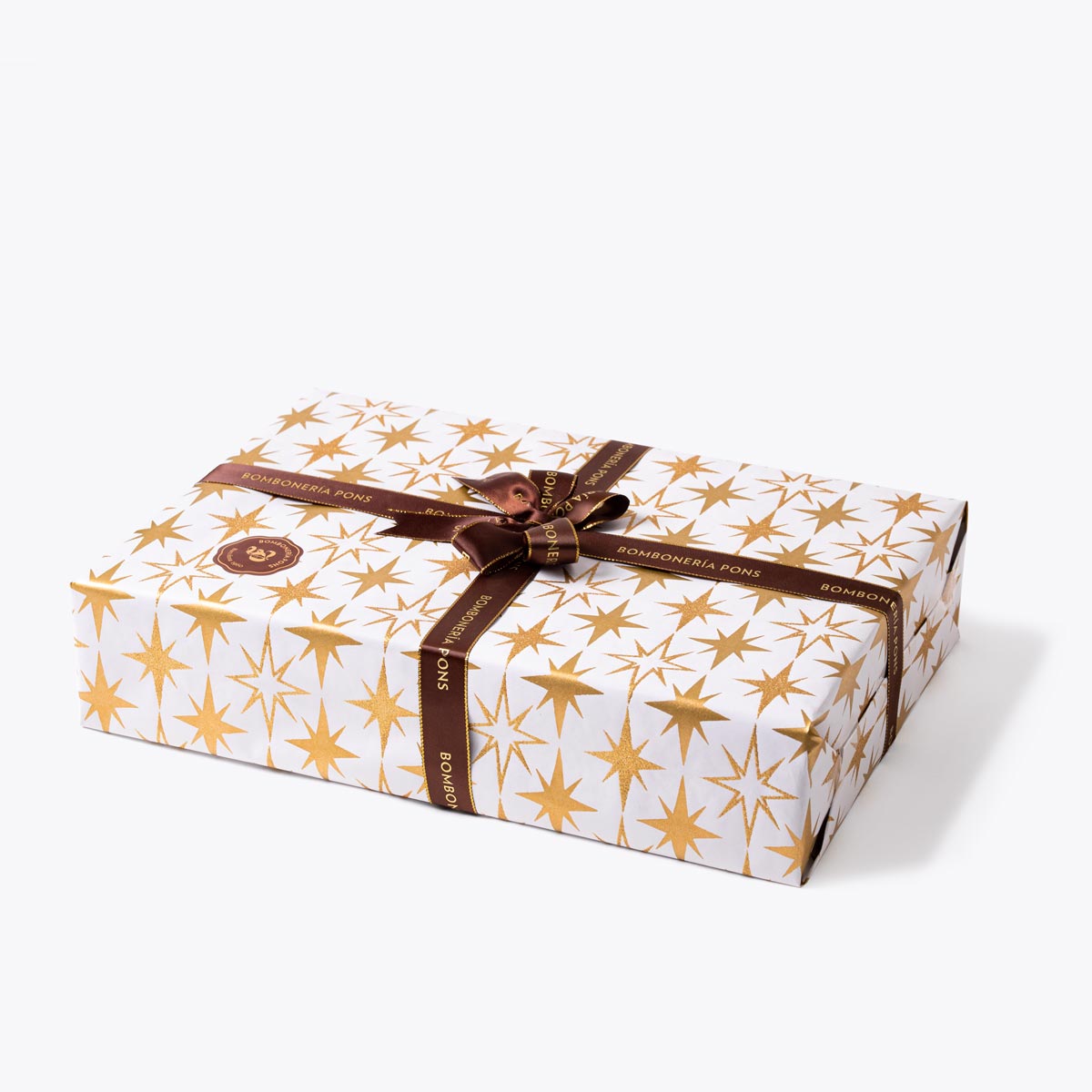 Caja dorada con papel de regalo blanco con estrellas doradas con un lazo marrón | Bombonería Pons